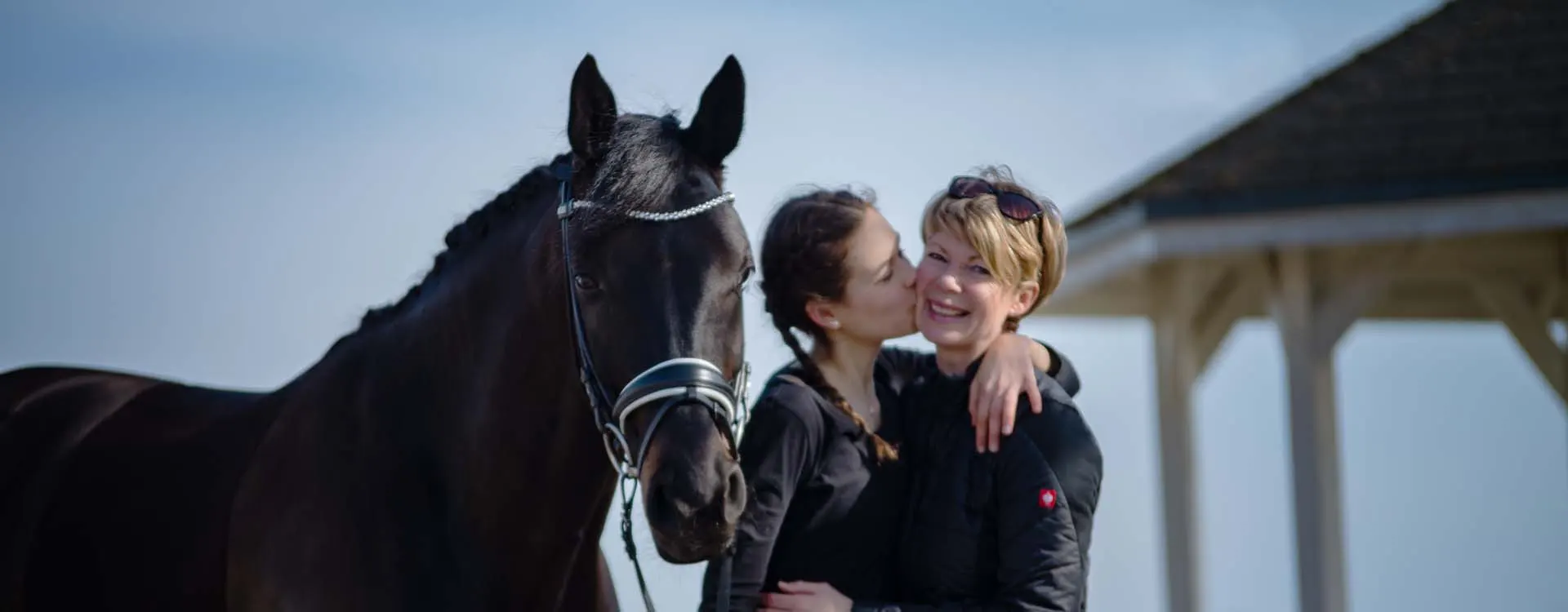 Foto von Karen van Hunnik-Bretfeld mit Tochter Linn und schwarzem Pferd.